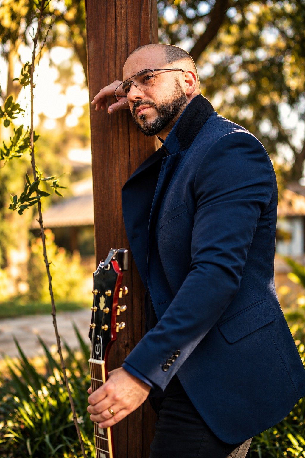 Thiago Azevedo com guitarra junto à coluna de madeira